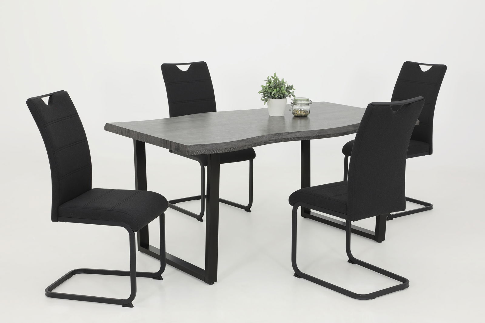 Esszimmer mit vier schwarzen Schwingstühlen und einem modernen Tisch aus dunklem Holz, seitliche Perspektive