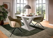 Modernes Esszimmer-Set mit weißem Esstisch mit V-Gestell und vier olivgrünen Polsterstühlen auf Teppich, Perspektive: leicht schräg von vorne auf Tisch und Stühle.