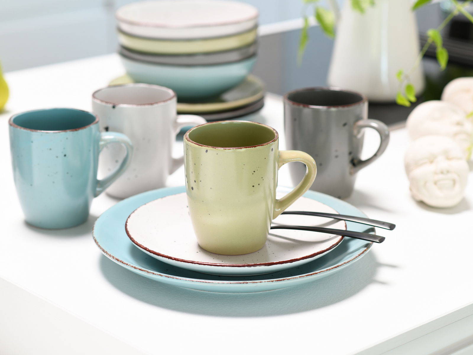Kombiservice 16-tlg. Fashion in verschiedenen Farben, bestehend aus Tassen und Tellern, aus der Vogelperspektive auf einem Tisch arrangiert.