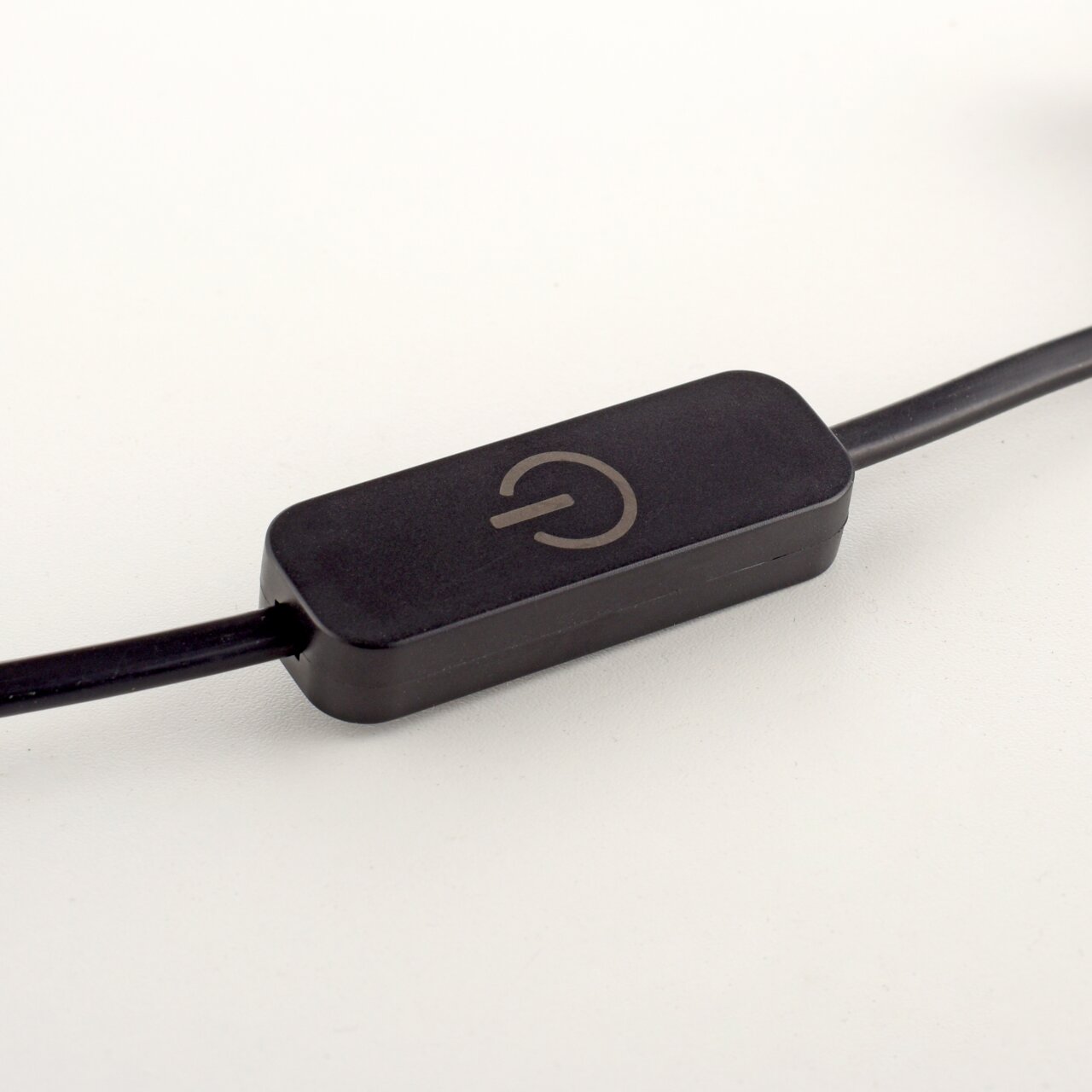 Nahaufnahme eines schwarzen Kabelschalters mit einem Ein-/Aussymbol, seitliche Perspektive.