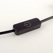 Nahaufnahme eines schwarzen Kabelschalters mit einem Ein-/Aussymbol, seitliche Perspektive.