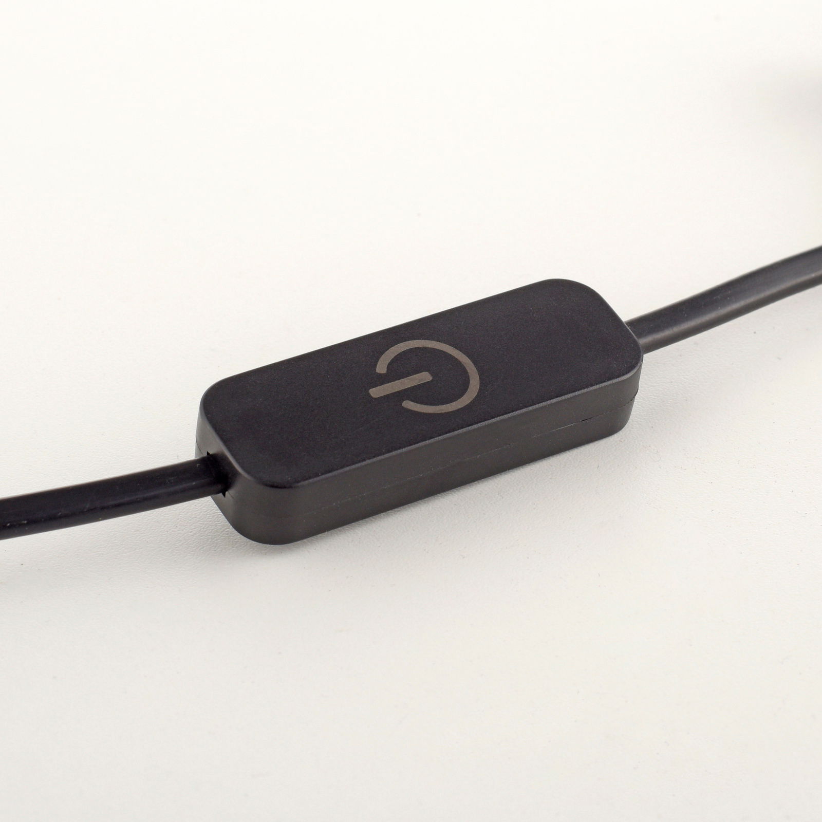 Nahaufnahme eines schwarzen Kabelschalters mit einem Ein-/Aussymbol, seitliche Perspektive.