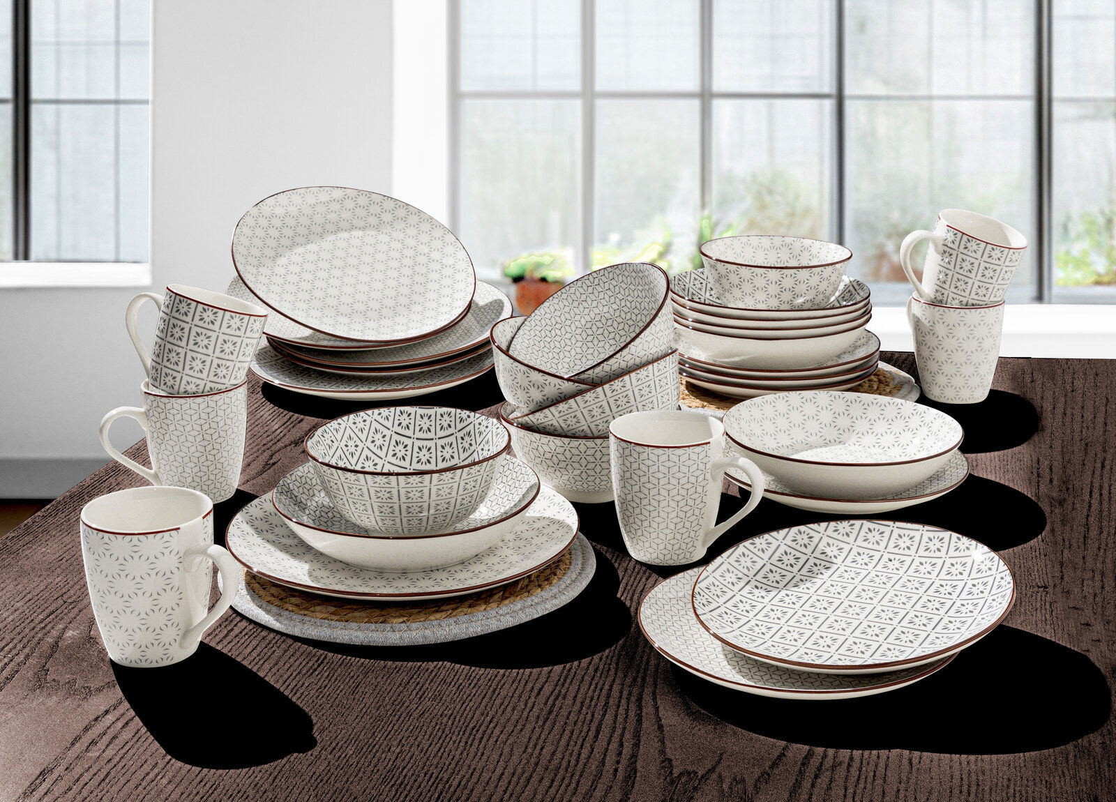 Kombiservice 30-teilig mit elegantem geometrischen Muster, bestehend aus Tellern, Schalen und Tassen, auf einem Tisch in einem hellen Raum präsentiert.