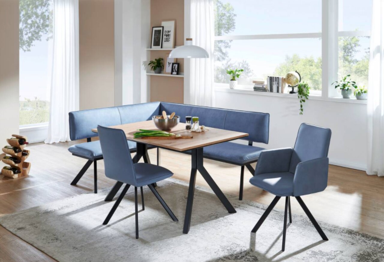 Moderne Esszimmer-Sitzgruppe mit blauer Eckbank und Stühlen, Tisch in Holzoptik, seitliche Perspektive