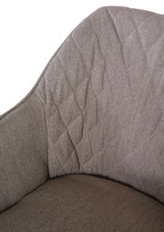 Nahaufnahme eines Armlehnstuhls mit gepolstertem, texturiertem Stoff in Beige, Ansicht von der Seite.