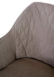 Nahaufnahme eines Armlehnstuhls mit gepolstertem, texturiertem Stoff in Beige, Ansicht von der Seite.