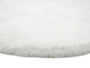 Nahaufnahme eines weißen, flauschigen Fellteppichs aus seitlicher Perspektive.