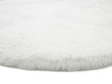 Nahaufnahme eines weißen, flauschigen Fellteppichs aus seitlicher Perspektive.