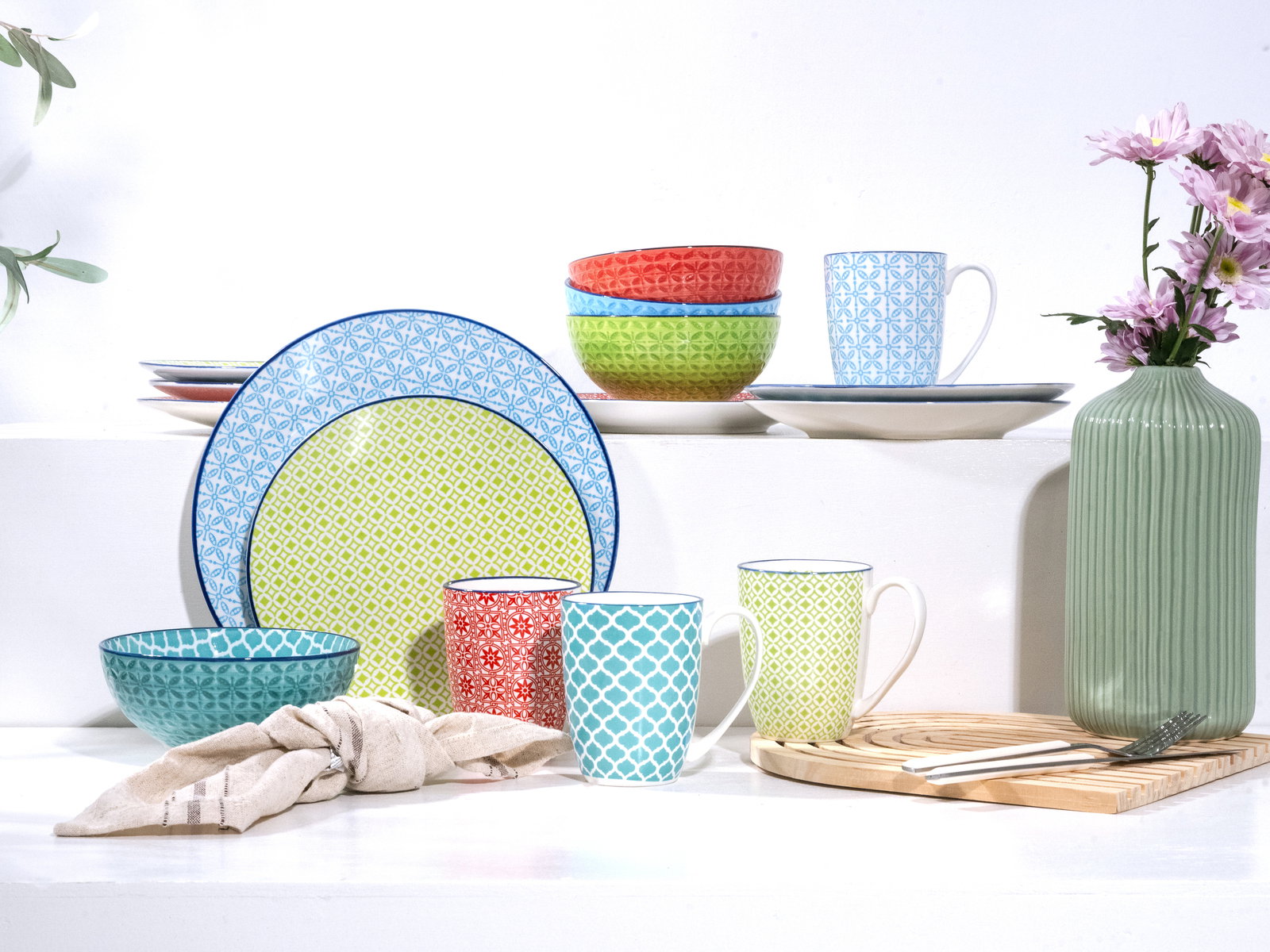 Buntes Kombiservice 16-tlg mit Tassen, Tellern und Schalen in verschiedenen Mustern und Farben, seitliche Perspektive