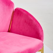 Nahaufnahme eines pinkfarbenen Sessels mit goldenen Akzenten, seitliche Perspektive