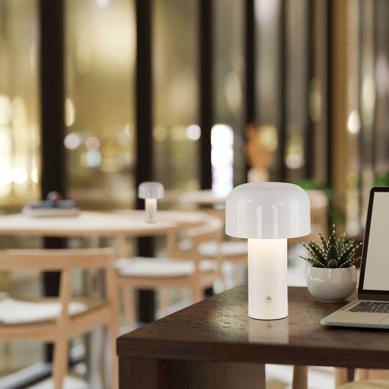 Just Light Akku-Tischleuchte AGNES Moderne Akku-Tischleuchte AGNES in einem stilvollen Innenraum, auf einem Tisch neben einem Laptop und einer Pflanze platziert, mit Blick auf einen gemütlichen Raum im Hintergrund.