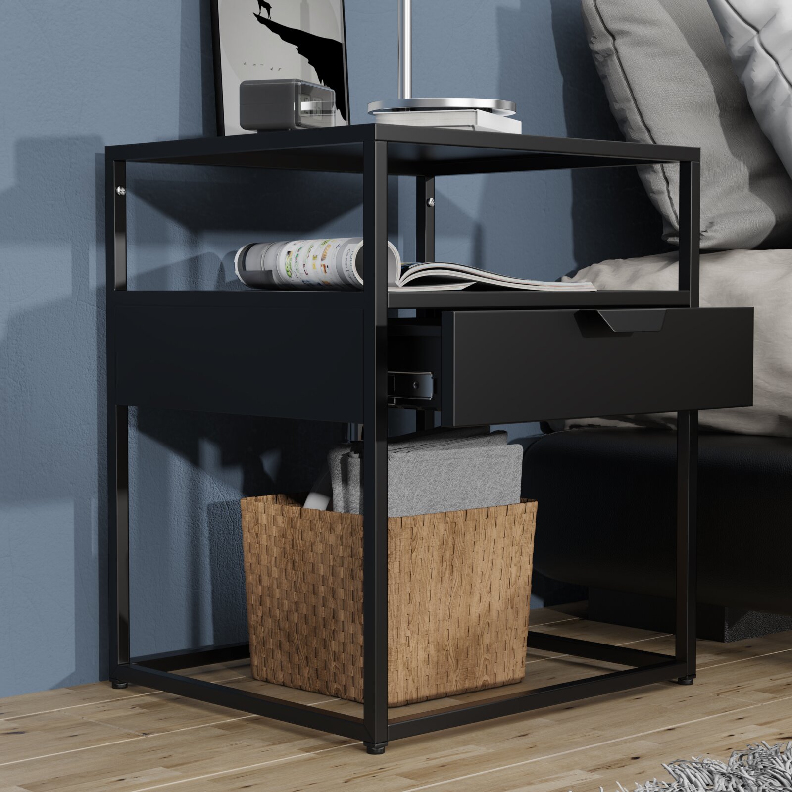 Schwarzer Nachttisch im modernen Metallrahmen-Design mit Ablagefach und halb geöffneter Schublade neben einem Bett, perspektivisch in seitlicher Frontansicht aufgenommen.
