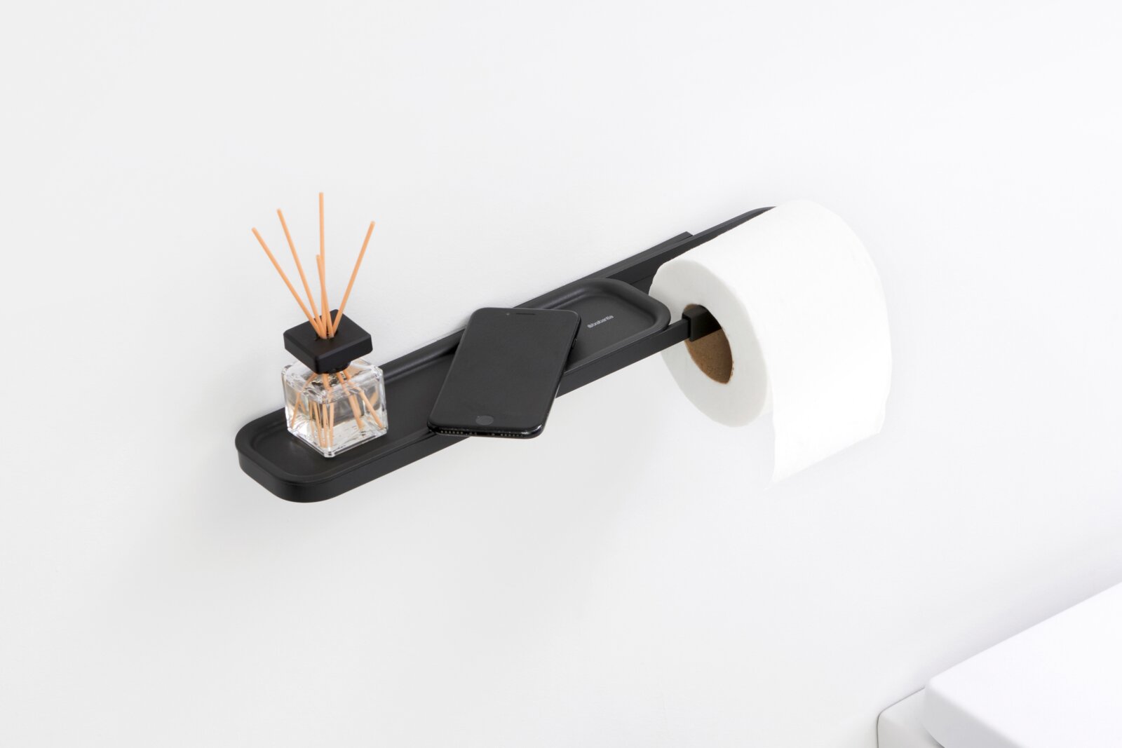 Brabantia Toilettenpapierhalter mit Abla MINDSET Schwarzer Toilettenpapierhalter mit Ablage, darauf ein Duftstäbchen-Glas und ein Smartphone, seitliche Perspektive
