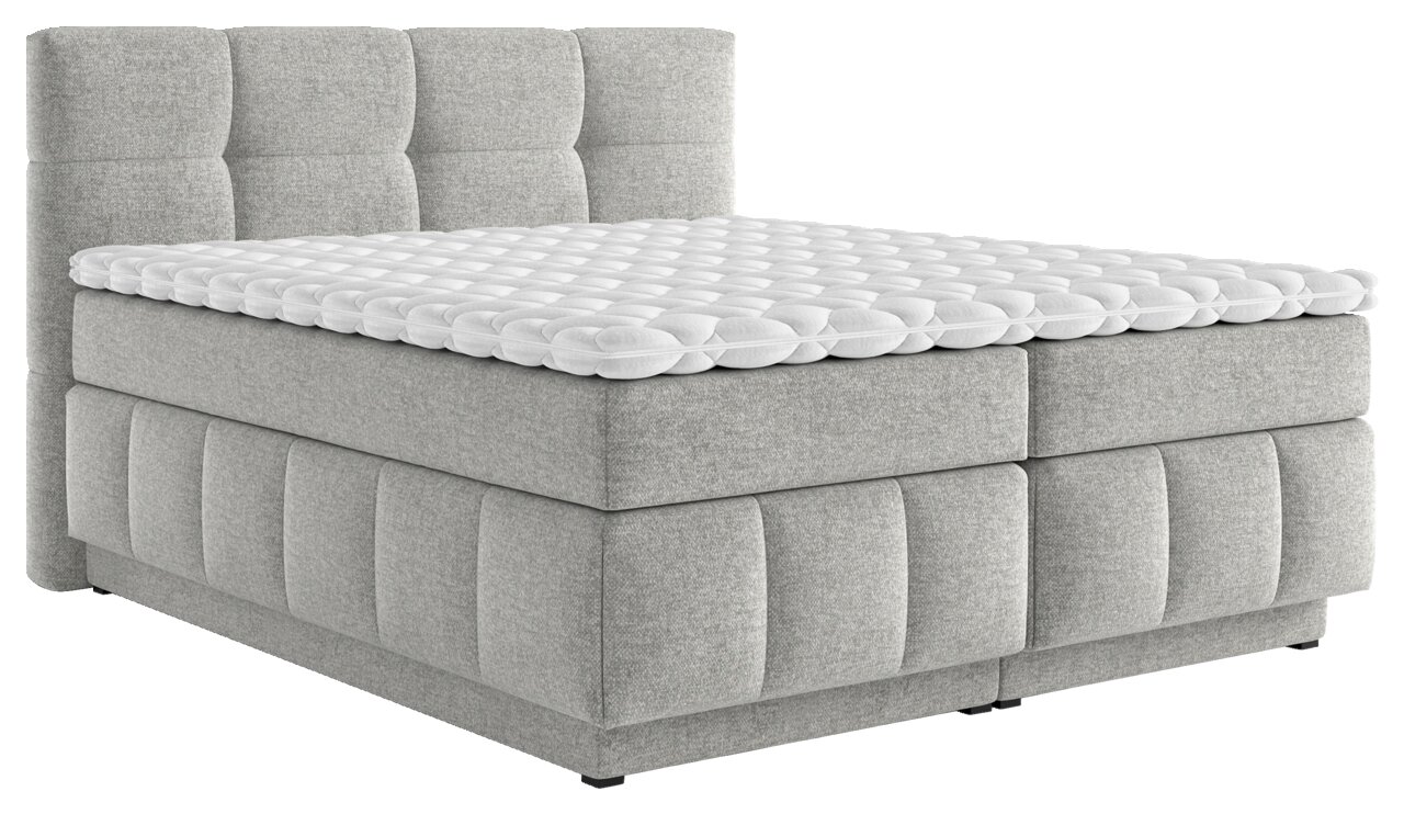 Graues Boxspringbett mit gepolstertem Kopfteil und weißem Topper, seitliche Perspektive