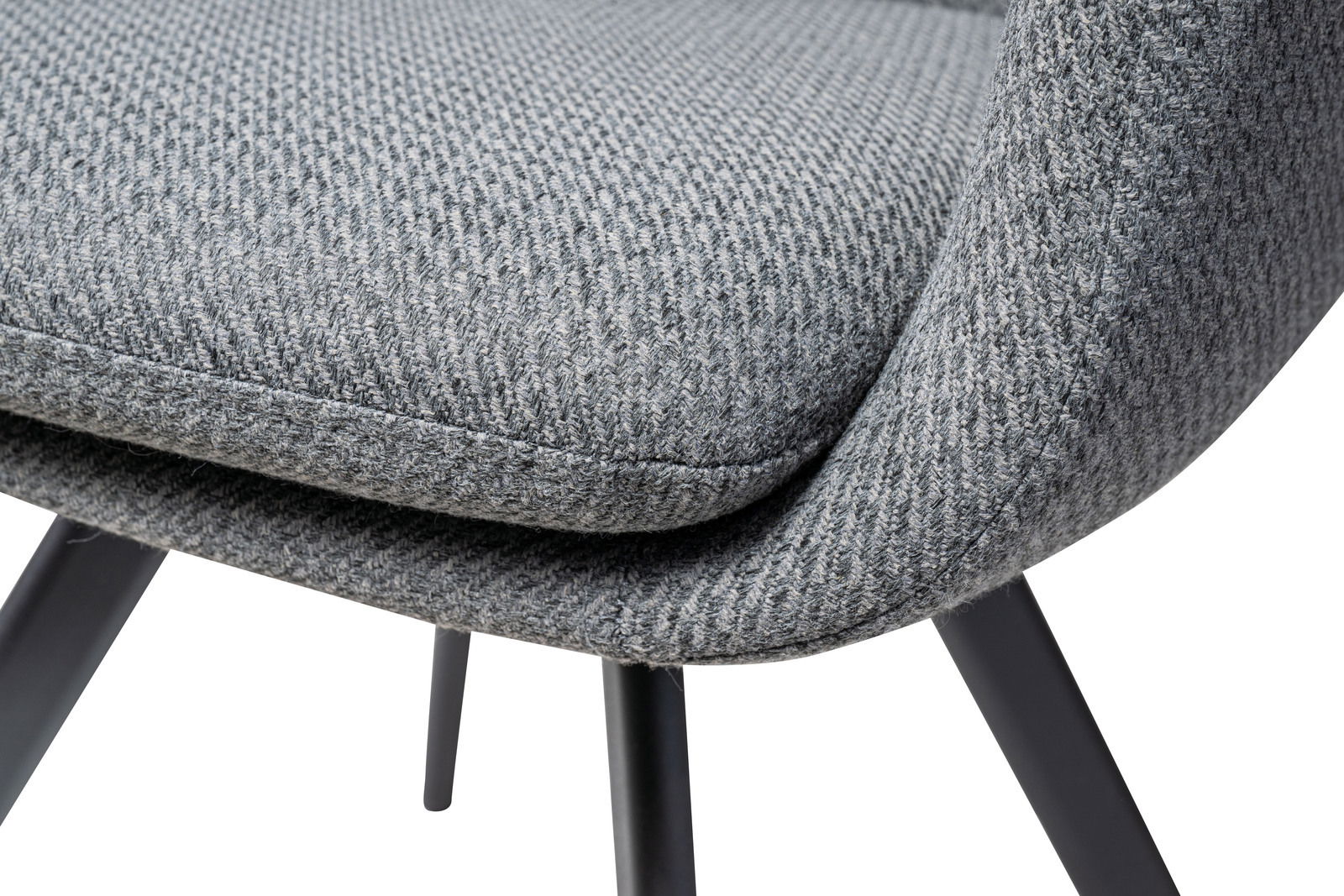 Nahaufnahme eines grauen Sessels mit texturierter Stoffoberfläche und schwarzen Metallbeinen, seitliche Perspektive.