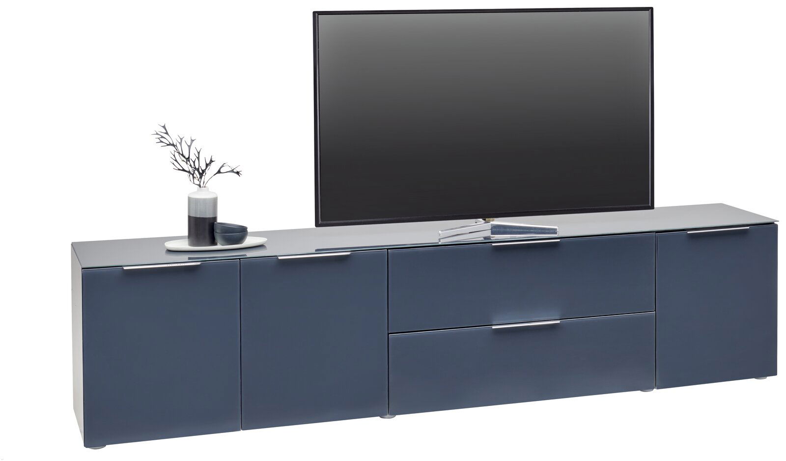 Frontansicht eines modernen XL-TV-Lowboards in dunklem Blau mit Dekoration und einem großen Fernseher darauf.