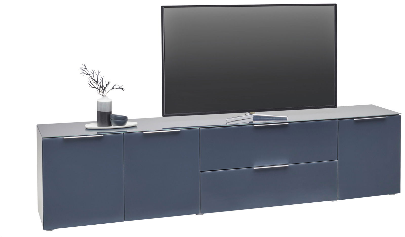 Frontansicht eines modernen XL-TV-Lowboards in dunklem Blau mit Dekoration und einem großen Fernseher darauf.
