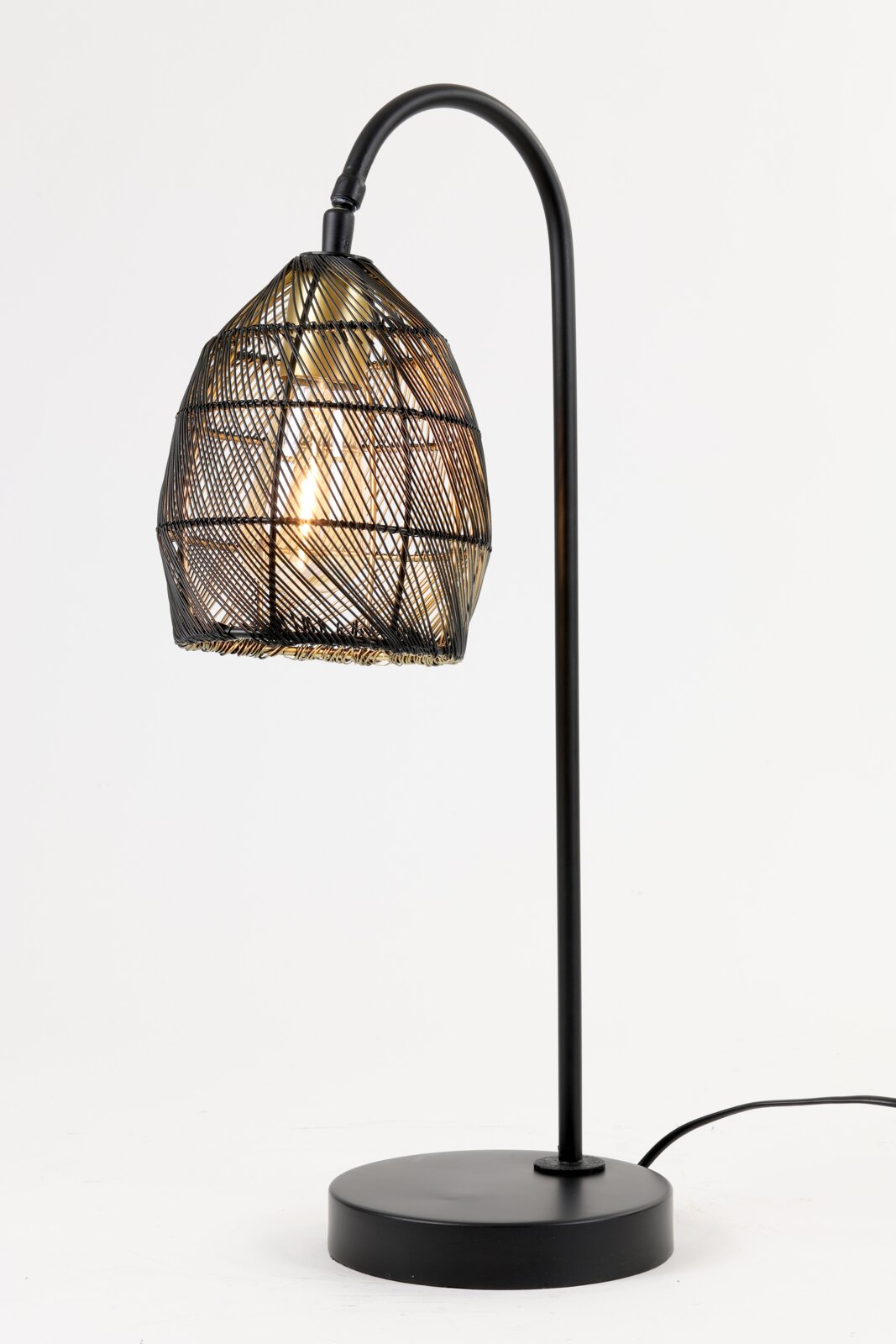 Zwarte tafellamp met gebogen standaard en sfeervol verlichte, gevlochten draadkap, vanuit schuin vooraanzicht op een witte achtergrond