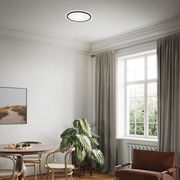 Moderne LED-Deckenleuchte in einem stilvoll eingerichteten Wohnzimmer, aus der Perspektive von unten betrachtet.