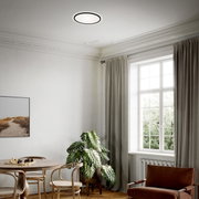 Moderne LED-Deckenleuchte in einem stilvoll eingerichteten Wohnzimmer, aus der Perspektive von unten betrachtet.