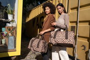Zwei Frauen halten Leo Macchiato Allrounder Taschen vor einem gelben Container. Die Taschen haben ein Leopardenmuster und sind aus der Perspektive von vorne zu sehen.