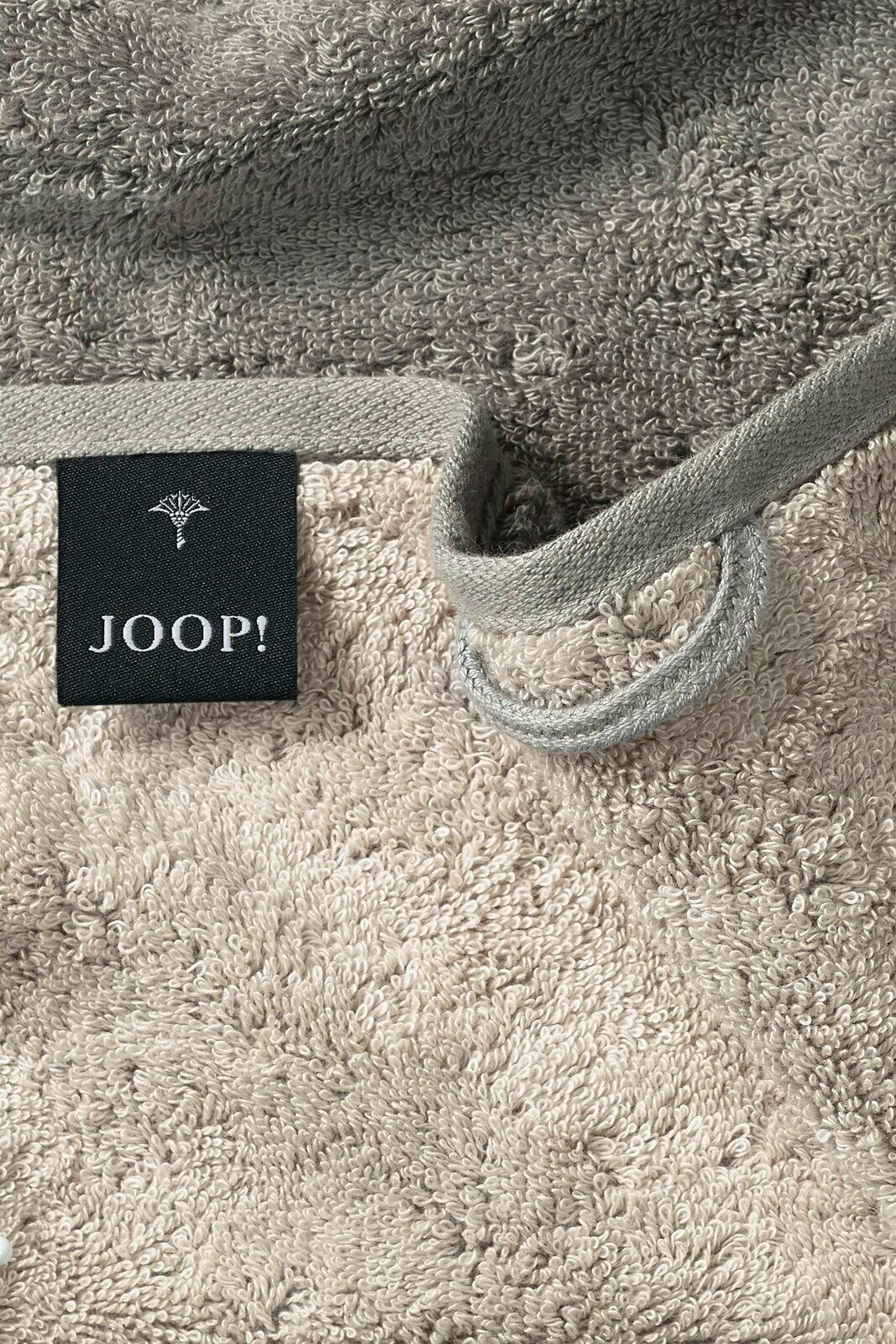 Nahaufnahme eines beigen Gästetuchs mit einer schwarzen Etikette mit der Aufschrift 'JOOP!' und einer Schlaufe zum Aufhängen.