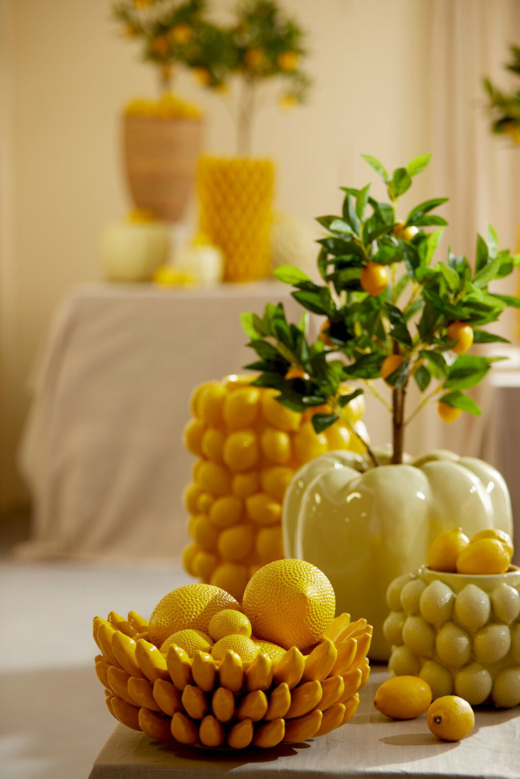 Light&Living Vase LEMON Vase in Form einer Zitrone, umgeben von dekorativen Zitronen und einem Zitronenbaum, aus der Vorderperspektive fotografiert.