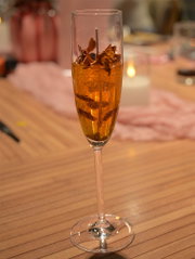 Goudkleurige kaars in een elegant champagneglas, afgewerkt met decoratieve bloemelementen.