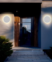 Moderne LED-Außenwandleuchte an einer Hausfassade, frontal betrachtet, mit warmem Lichtschein.