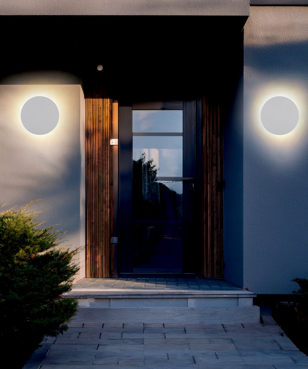 Moderne LED-Außenwandleuchte an einer Hausfassade, frontal betrachtet, mit warmem Lichtschein.