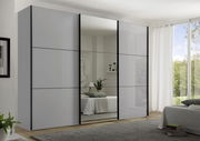 Moderano Schwebetürenschrank PRIMO in einem modernen Schlafzimmer, frontal betrachtet, mit einem großen Spiegel in der Mitte und eleganten, grauen Türen.