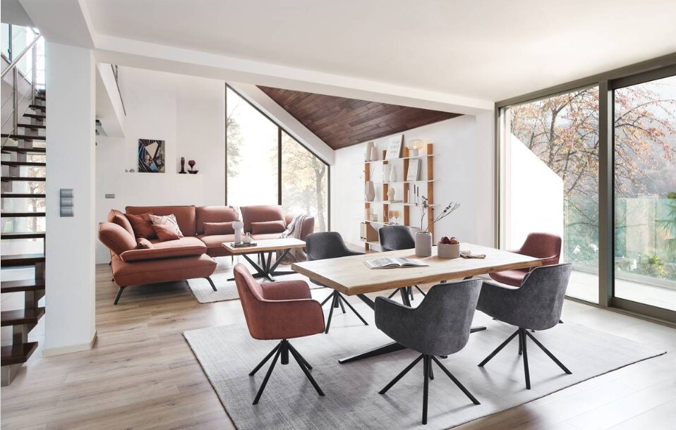 Moderner Esstisch in einem hellen, offenen Wohnbereich mit großen Fenstern und stilvollen Stühlen, seitliche Perspektive.