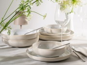 Elegantes cremefarbenes Keramikgeschirr mit Tellern und Schalen auf einer festlich gedeckten Tafel, aus leicht erhöhter frontaler Perspektive inszeniert