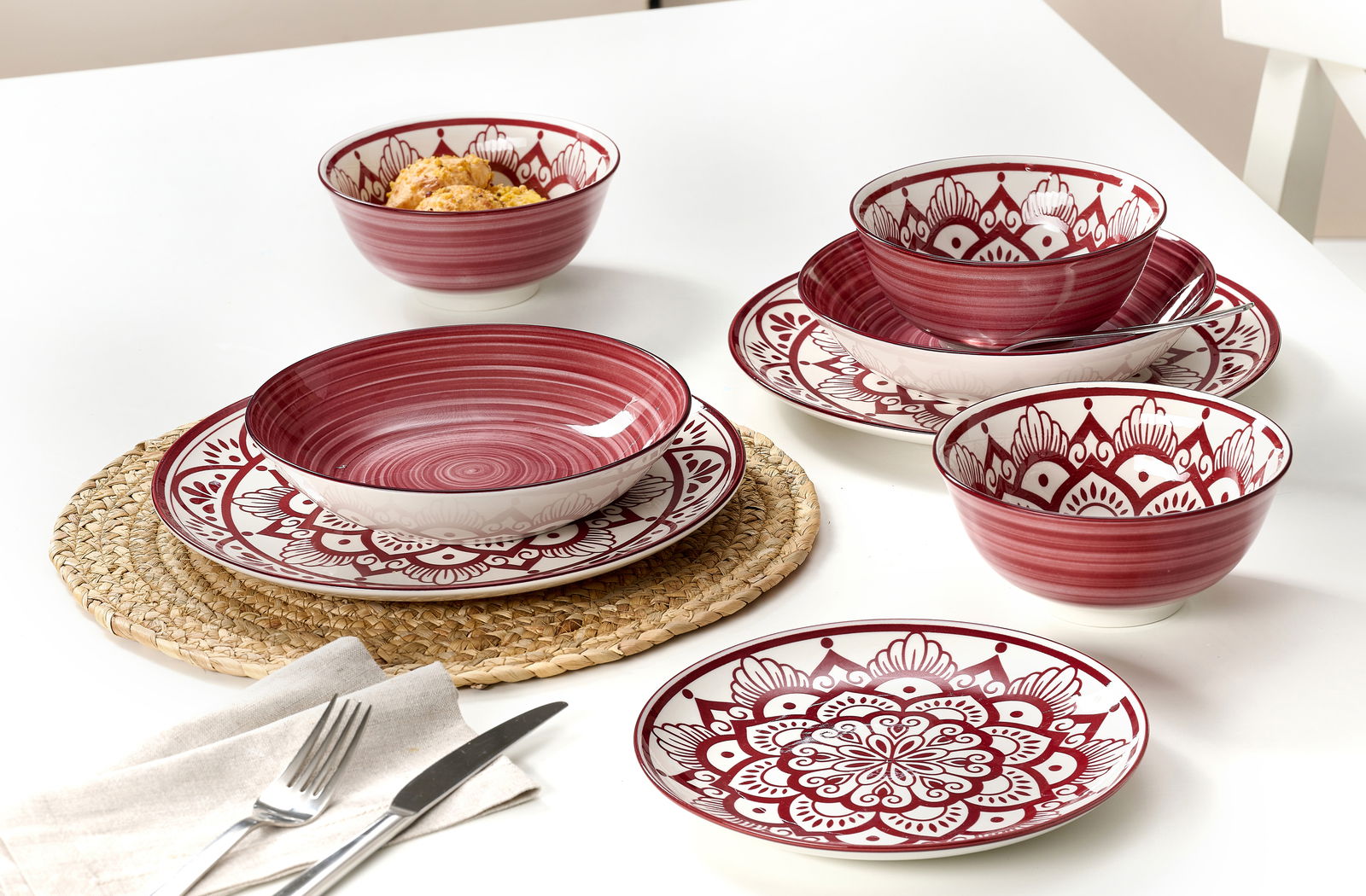 Tellerset 16-tlg. in Burgund mit dekorativem Muster, aus der Vogelperspektive auf einem weißen Tisch arrangiert.
