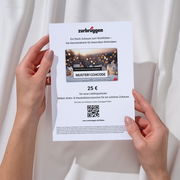 Zwei Hände halten eine Zurbrüggen-Geschenkkarte im Wert von 25 Euro, mit einem QR-Code und einem Code zum Einlösen. Perspektive von oben auf die Karte.