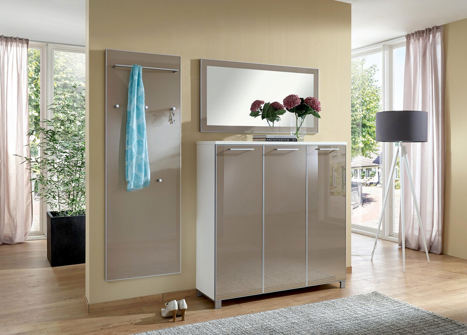 Moderner rechteckiger Wandspiegel in einem eleganten Raum mit natürlichem Licht, neben einem Schrank und einer Stehlampe, aus der Perspektive des Betrachters leicht von der Seite gesehen.