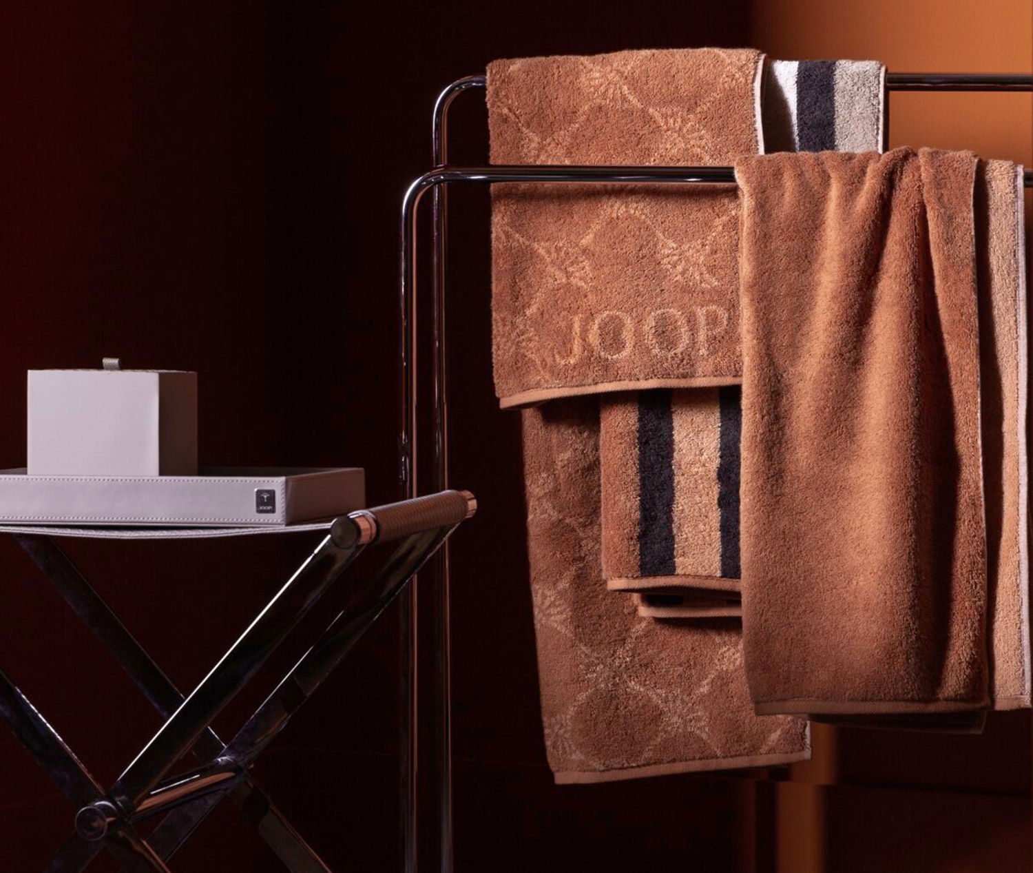 Braune Handtücher, die auf einem Gestell neben einem modernen Beistelltisch mit einer dekorativen Box hängen.