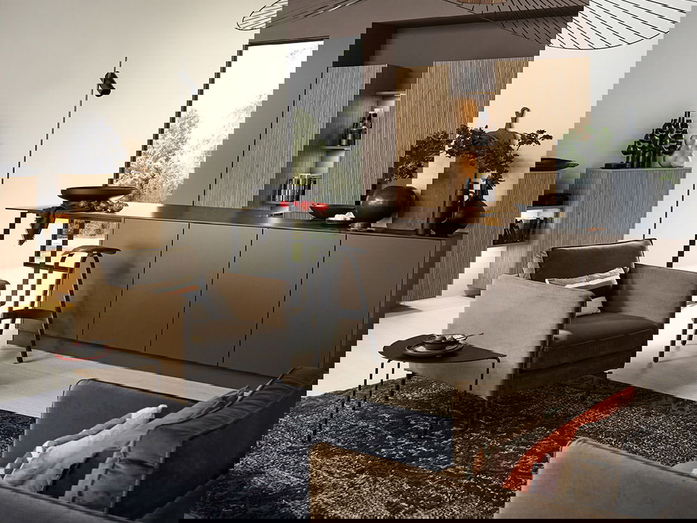 Moderne, offene Wohnküche in warmen Brauntönen mit gemütlicher Sitzecke, eleganten Holzelementen und stilvoller Dekoration.