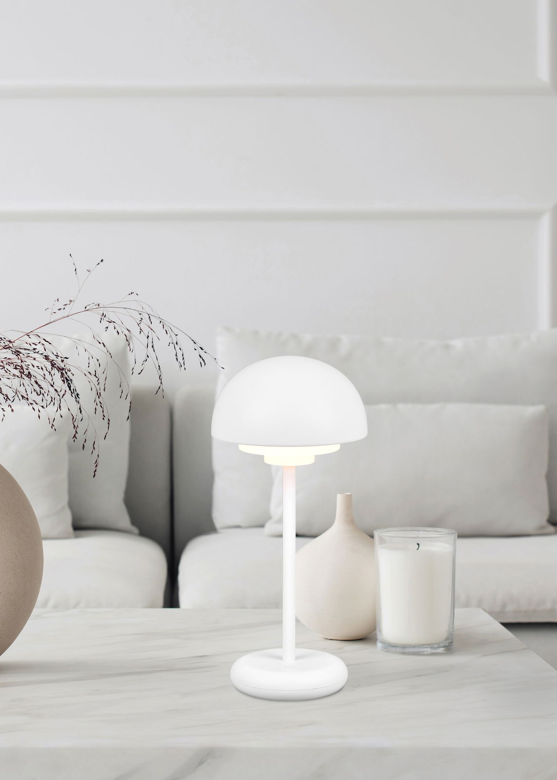 Moderne Akku-Tischleuchte ELLIOT in Weiß auf einem Tisch in einem stilvollen Wohnzimmer, seitliche Perspektive.
