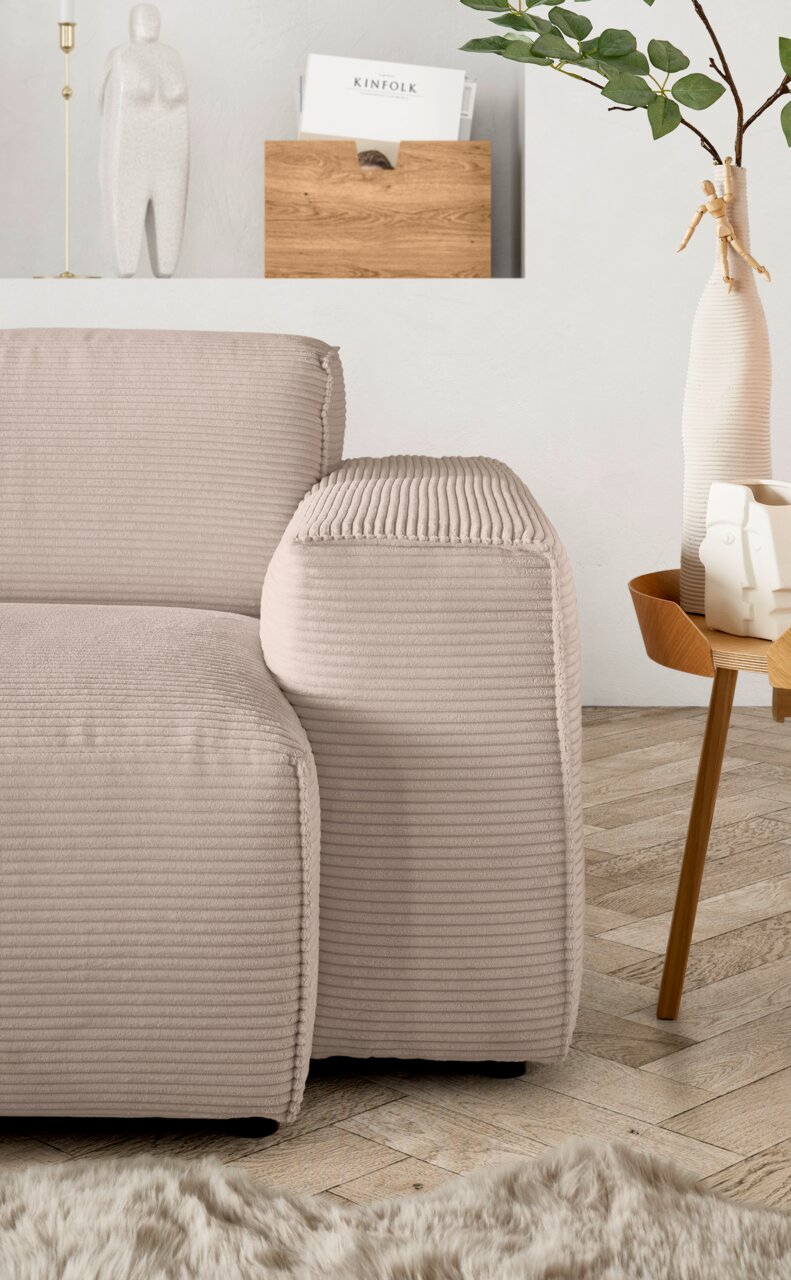 Beige Sofa-Ecke mit geripptem Stoff, seitliche Perspektive, neben einem Holztisch mit Dekorationen.