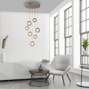 Moderne LED-Pendelleuchte mit mehreren Glaskugeln, hängend von der Decke in einem stilvollen Wohnzimmer mit großen Fenstern, seitliche Perspektive.