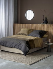 Bett mit gestreifter Bettwäsche in Erdtönen, seitliche Perspektive, modernes Schlafzimmerdesign