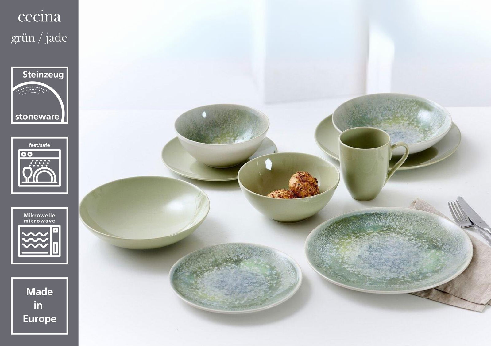 Steinzeug-Geschirrset in Jadegrün, bestehend aus flachen Tellern, Schalen und Tassen, auf einem Tisch arrangiert. Perspektive von oben.