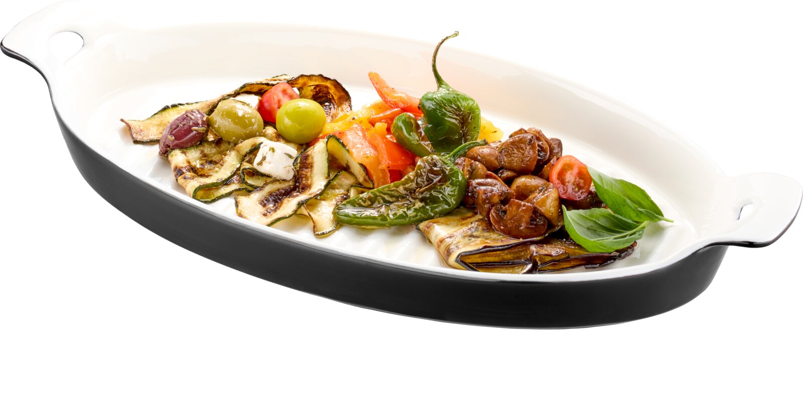 Ovale weiße Auflaufform mit Griffen, gefüllt mit gegrilltem mediterranem Gemüse, Oliven und Basilikum, in schräger Seitenansicht von oben auf weißem Hintergrund