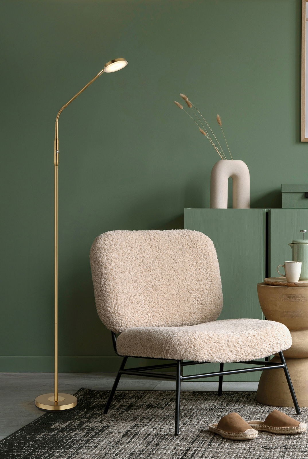 Elegante LED-Stehleuchte in Gold neben einem gemütlichen Sessel in einem stilvoll eingerichteten Raum, seitliche Perspektive