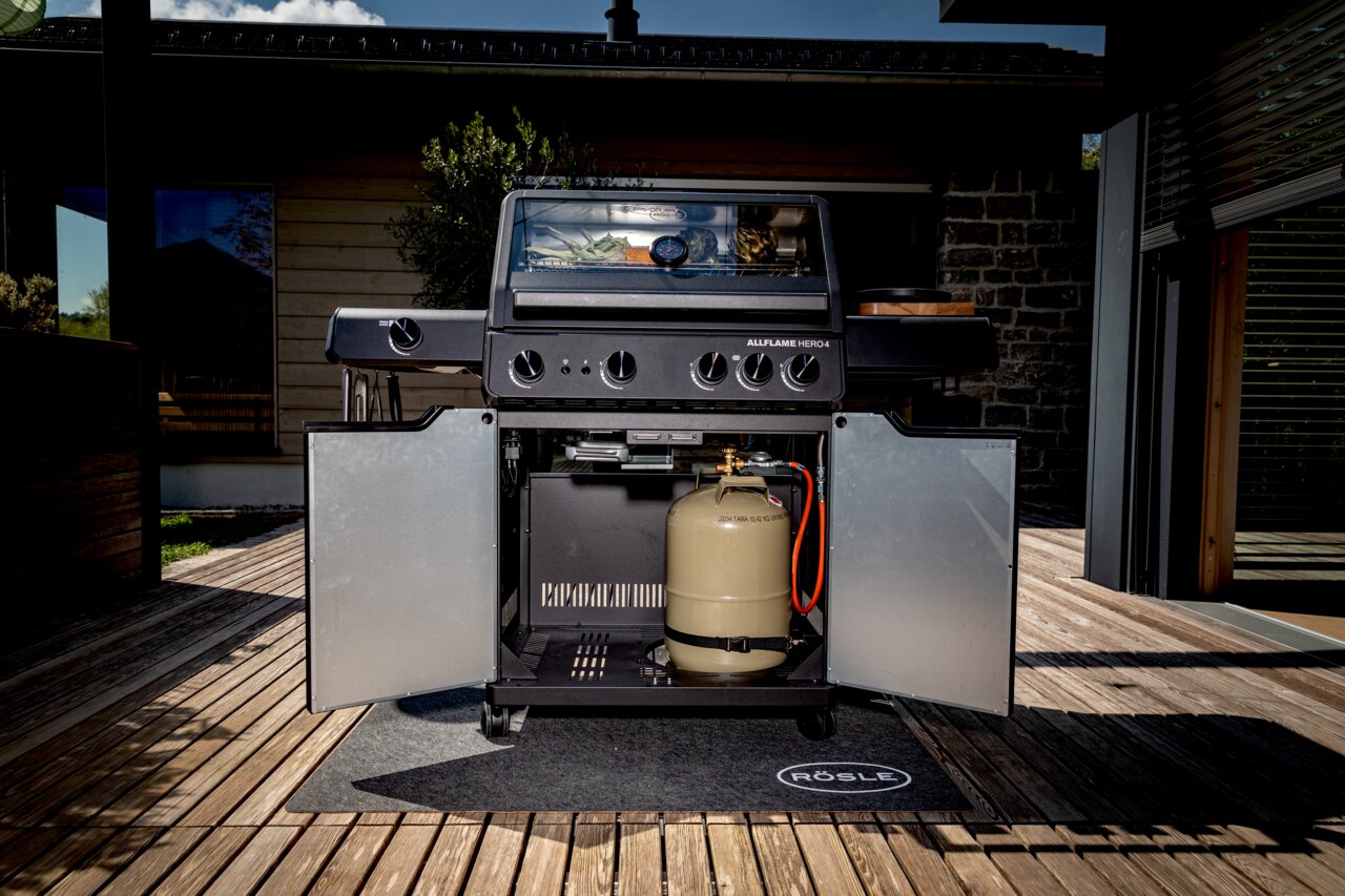 Frontansicht des Gasgrills Allflame Hero 4 mit geöffneten Türen, sichtbarer Gasflasche und Grillfläche.