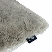 Nahaufnahme eines weichen, grauen Kunstfellkissens mit Joop-Label.