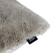 Nahaufnahme eines weichen, grauen Kunstfellkissens mit Joop-Label.