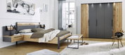 Moderne slaapkamer met een houten bed en nachtkastjes, een grote kledingkast en een raam op de achtergrond. Aanzicht vanaf de zijkant van het bed.