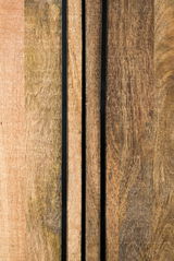 Nahaufnahme von Holzoberflächen mit vertikalen schwarzen Streifen, perspektivisch von vorne betrachtet.
